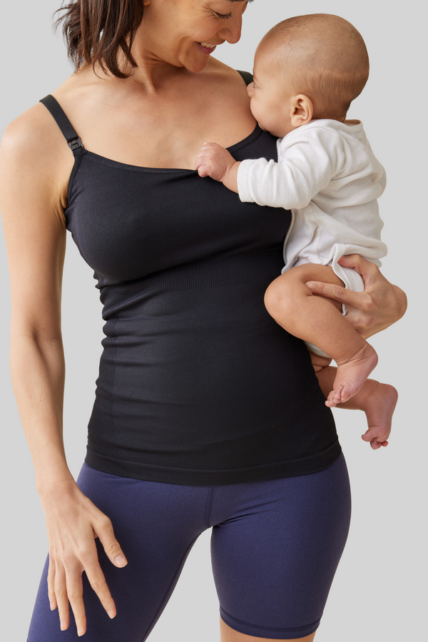 ||Woman in black tank top and blue bike shorts holding a baby