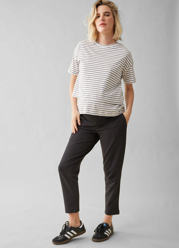 ||Woman wearing a striped shirt and black pants on a gray background