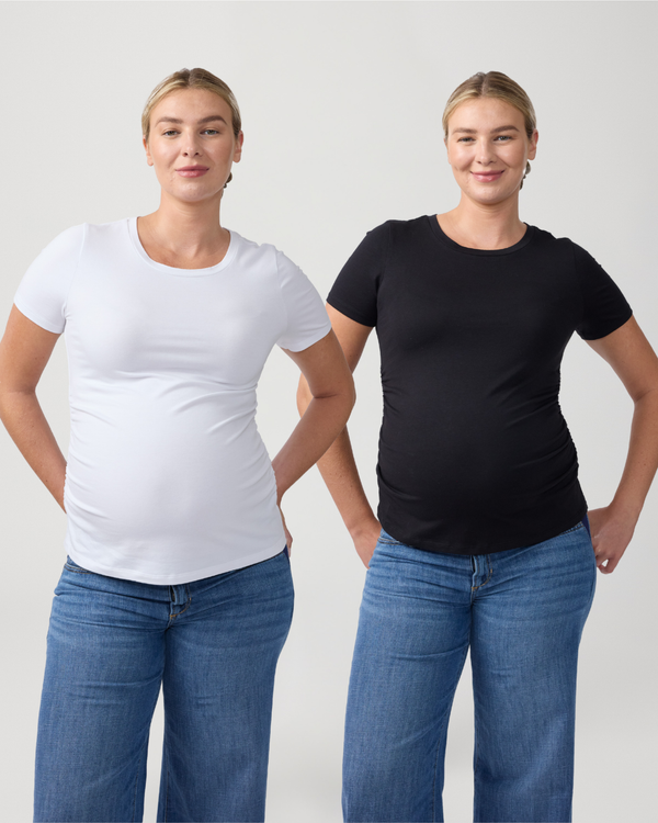 Two identical women wearing blue denim jeans, one in a white core maternity tee, and the other in black