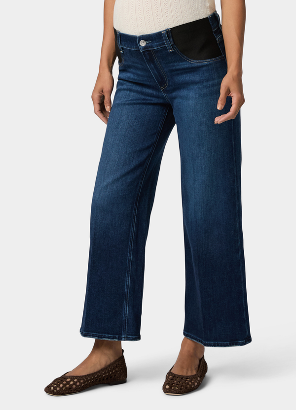 ||A half body shot of a pregnant woman wearing high rise wide leg maternity jeans with brown flats