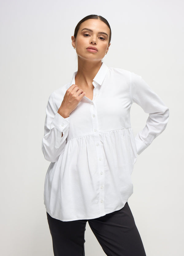 ||Pregnant woman wearing white peplum button down top and black pants on a plain background