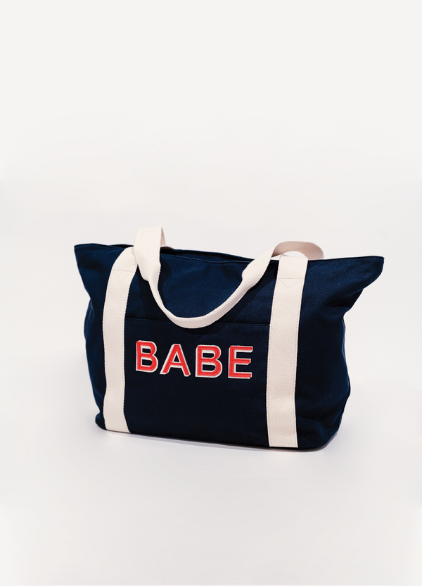 ||A navy-colored cotton tote bag with the word 'BABE' written in red letters on the side, featuring white straps.