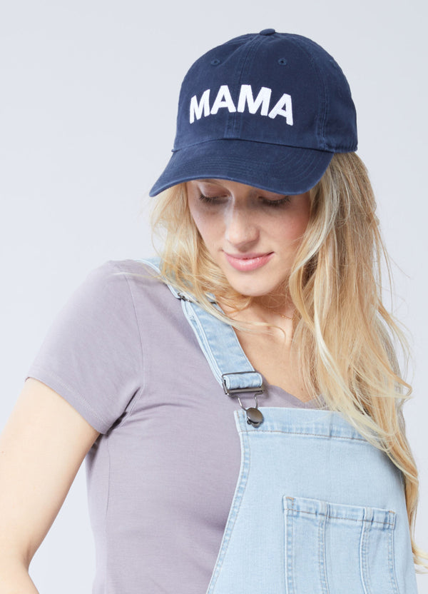 A blonde woman wearing a navy baseball cap with the word 'MAMA' embroidered on the front.